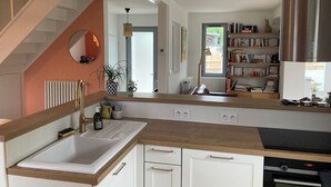 A modern kitchen with a wooden countertop, white cabinets, a built-in oven, and a bookshelf filled with books. - Charming house 3 kms from Caen.  Comfort, light, location -> Coup de coeur! (Fleury-sur-Orne)