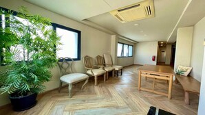 Une pièce spacieuse avec une grande plante en pot, une table en bois et deux fauteuils rembourrés.