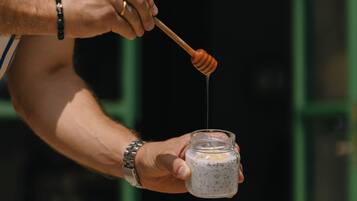 A person pouring honey from a jar onto a plate with croissants.