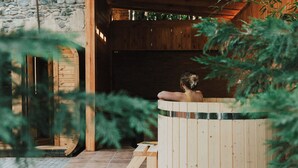 A wooden sauna with a bench, a stone wall, and a wooden door. - Hameau Mukhrani (Mtskheta)