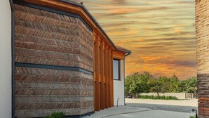 A modern building with a curved facade, a wooden door, and a brick wall. - Hameau Mukhrani (Mtskheta)