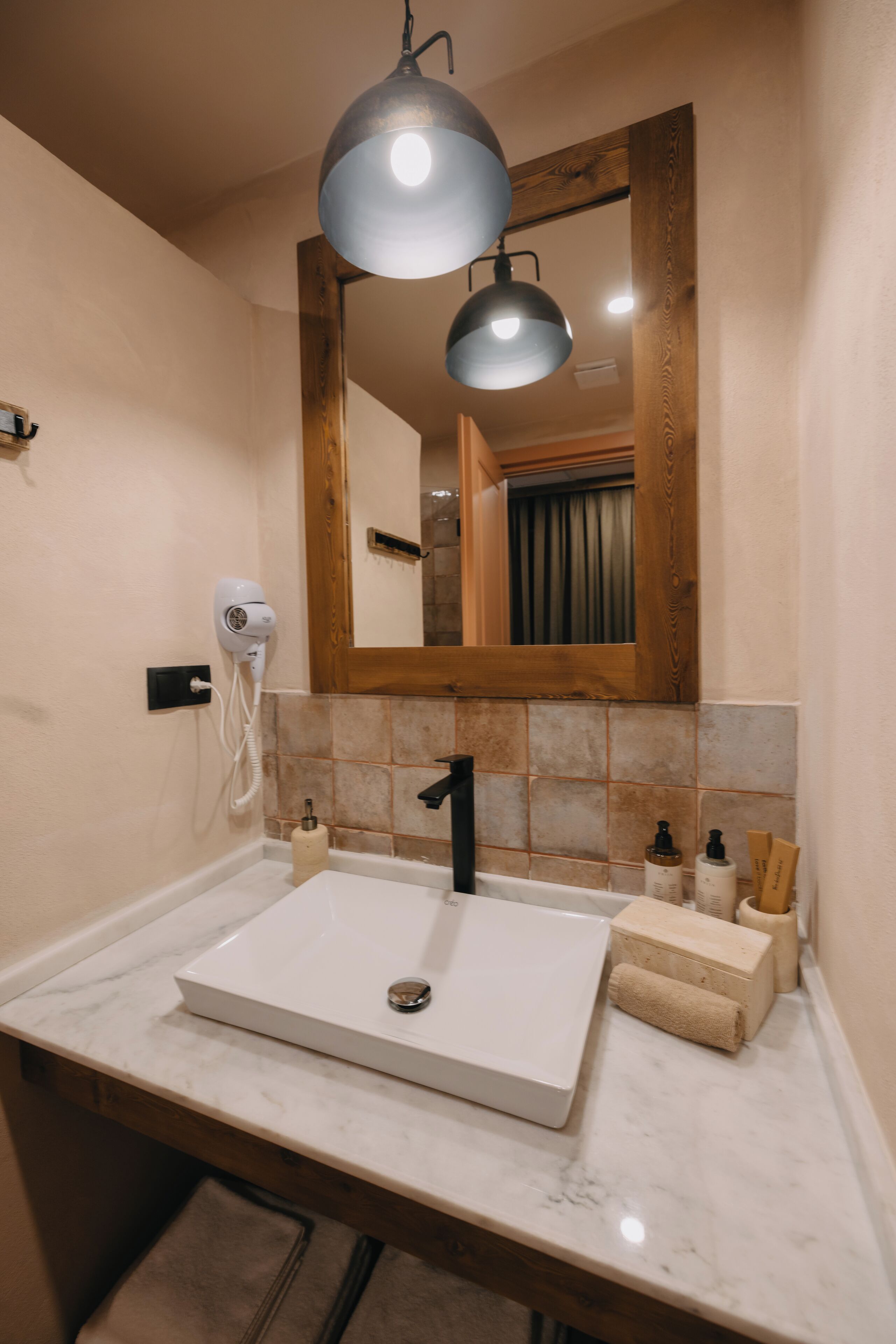 A bathroom with a white sink, a mirror, and a hairdryer mounted on the wall.
