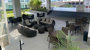 A spacious outdoor seating area with modern furniture, including sofas and chairs, and a view of a building in the background. - Davao Central Suites (Davao City)