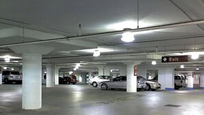 A multi-level underground parking garage with several cars parked, concrete pillars, and an exit sign. - Davao Central Suites (Davao City)