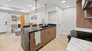 A modern kitchen with a central island, wooden cabinets, and a black countertop.