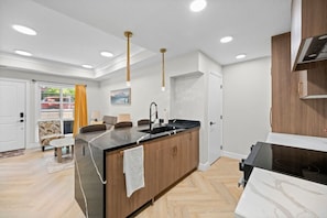 Cozinha moderna com ilha central, armários de madeira e bancada preta.