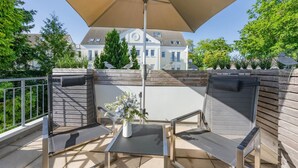 An outdoor patio with a table and chairs, a large umbrella, and a view of a house in the background.