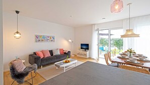 Un salon moderne comprenant un canapé, une table basse, un téléviseur, un coin repas et de grandes fenêtres.