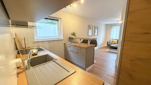 A modern kitchen with a wooden countertop, built-in dishwasher, and a window above the sink. - Casa Limone - Exclusive relaxation by the Baltic Sea - stylish living in Scharbeutz (Scharbeutz)