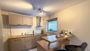 A modern kitchen with a built-in oven, a sink, and a window with blinds. - Casa Limone - Exclusive relaxation by the Baltic Sea - stylish living in Scharbeutz (Scharbeutz)