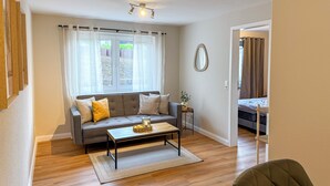 A living room with a sofa, coffee table, and a small side table with a plant. - Casa Limone - Exclusive relaxation by the Baltic Sea - stylish living in Scharbeutz (Scharbeutz)
