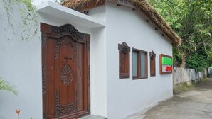 A traditional house with a wooden door and windows, a thatched roof, and a white exterior wall. - Abams Gili Air (Gili Air)