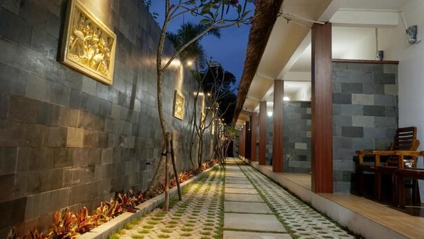 A corridor with stone walls, a patterned floor, and a dining area with chairs and a table. - Abams Gili Air (Gili Air)