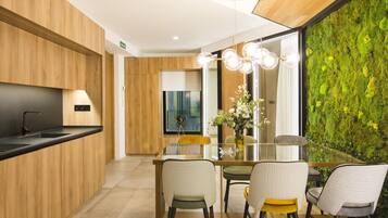 Une cuisine moderne avec des meubles en bois, un plan de travail noir et un coin repas comprenant une table et des chaises en verre.