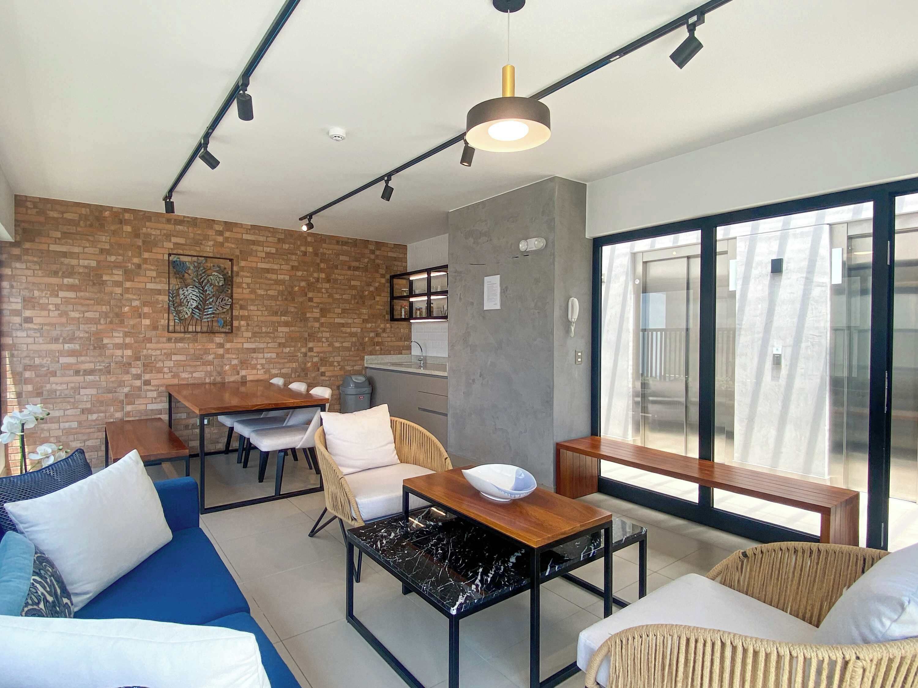 A modern living space with a dining area, a sofa, a coffee table, and a view of the outside.