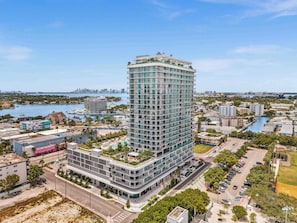 A high-rise hotel with multiple floors, a rooftop garden, and a view of the surrounding cityscape and water.
