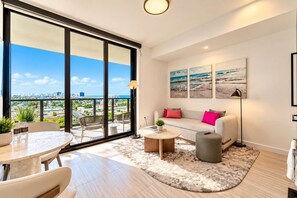 A modern living room with a large balcony, a sofa set, a coffee table, and a city view.