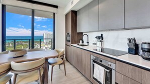 Une cuisine moderne avec vue sur l’océan, un coin repas avec des chaises et une machine à café.