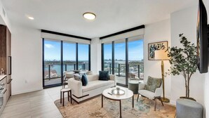 A modern living room with a sofa, coffee table, and a view of the city. - NEW: Above Miami Beach | Stylish 2BR/2BA, 14th (Miami Beach)
