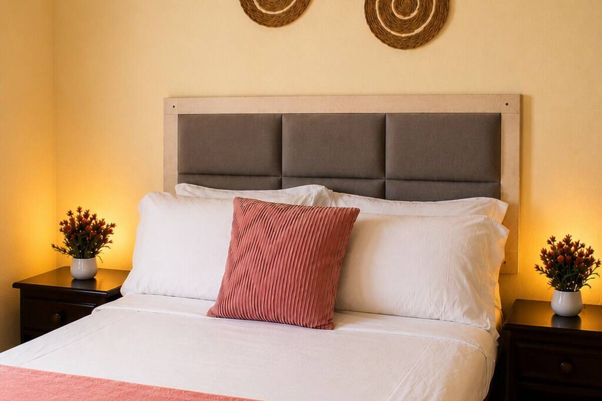 A neatly made bed with a grey headboard, two bedside tables with lamps, and decorative wall art.