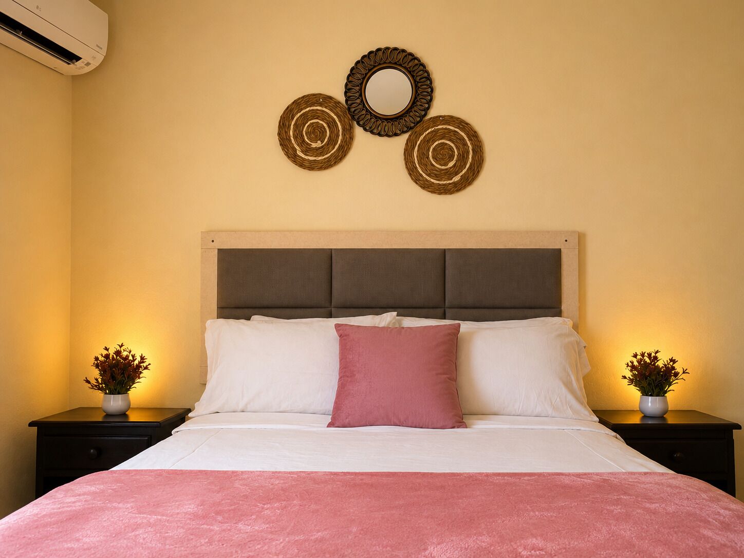 Una cama con cabecera, dos mesitas de noche con lámparas y decoración en la pared.