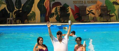 A swimming pool area with a mural depicting tropical plants and the text "HOTEL CROWN MIRAGE SUITES & CASINO".