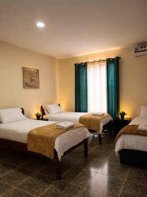 A hotel room with three beds, a painting on the wall, and a window with curtains. - Hotel Crown Mirage (David Sur)