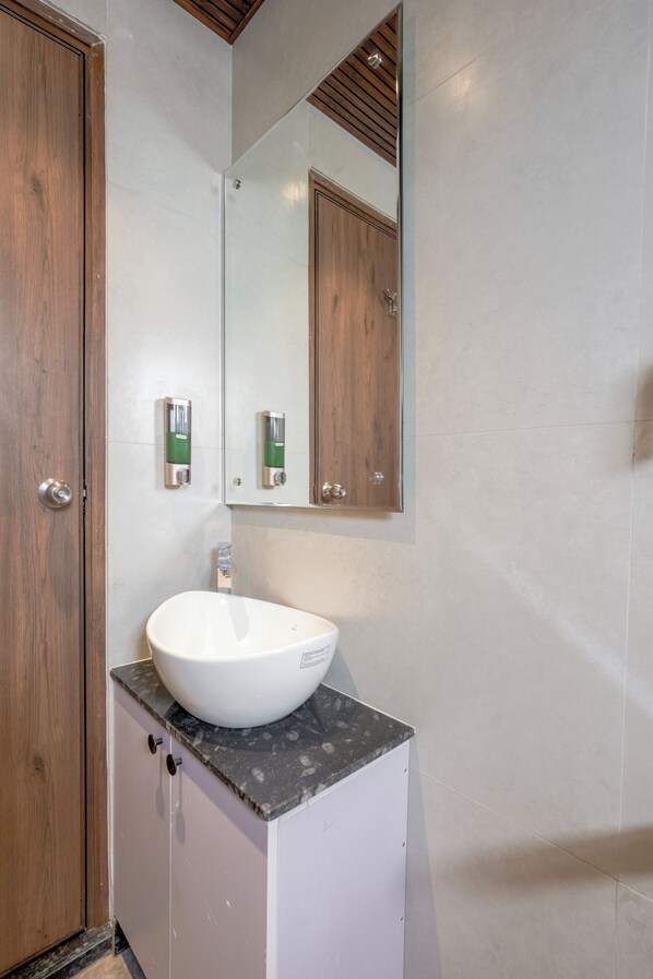 A bathroom with a white sink, wooden door, and a mirror above it.