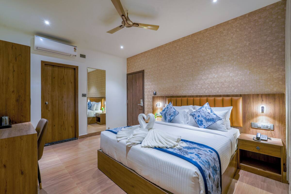 Habitación de hotel con una cama grande, cabecera de madera, un escritorio y un espejo.
