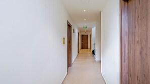 A long, narrow hallway with wooden doors and a tiled floor. - Royal Mark (Bengaluru)