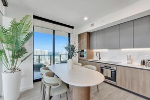 Une cuisine moderne dotée d’un grand îlot central, d’appareils électroménagers intégrés et offrant une vue sur la ville.