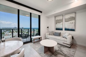 A modern living room with a balcony, a sofa, a round table, and two chairs.
