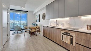 A modern kitchen with a built-in oven, a sink, and a dining area with a view of the city.