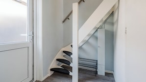 Una escalera moderna con barandilla blanca y escalones oscuros, que sube a un piso superior.