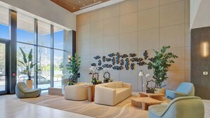 A modern lobby with large windows, seating areas, and decorative wall art. - 20th Floor Luxe Escape | Pool, Gym & Beach Access (Miami Beach)
