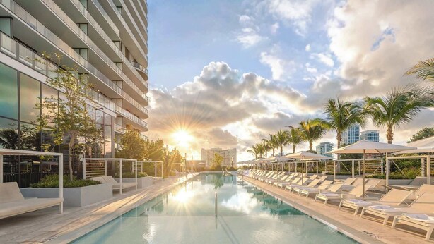 A modern hotel with a swimming pool, sun loungers, and palm trees. - 20th Floor Urban Coastal Escape | Oceanview 1BR (Miami Beach)