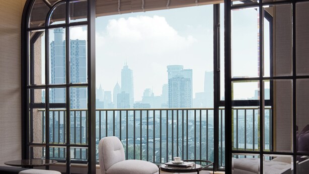 A modern living room with a large window, a sofa, a coffee table, and a view of a city skyline. - Haig Court (Shanghai)