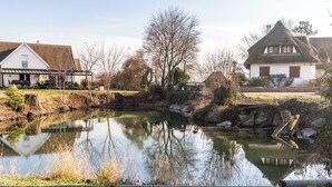 Un étang avec une maison et une grange en arrière-plan.