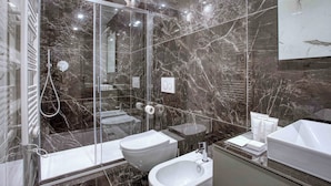 A modern bathroom with a glass-enclosed shower, a white sink, and a vanity with toiletries.