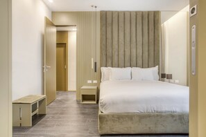 A modern hotel room with a large bed, bedside tables, a bench, and a wall-mounted panel. - Boutique Aparthotel By OSPITAMI (Milan)