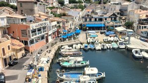 A marina with boats docked, surrounded by buildings with balconies and outdoor seating areas.