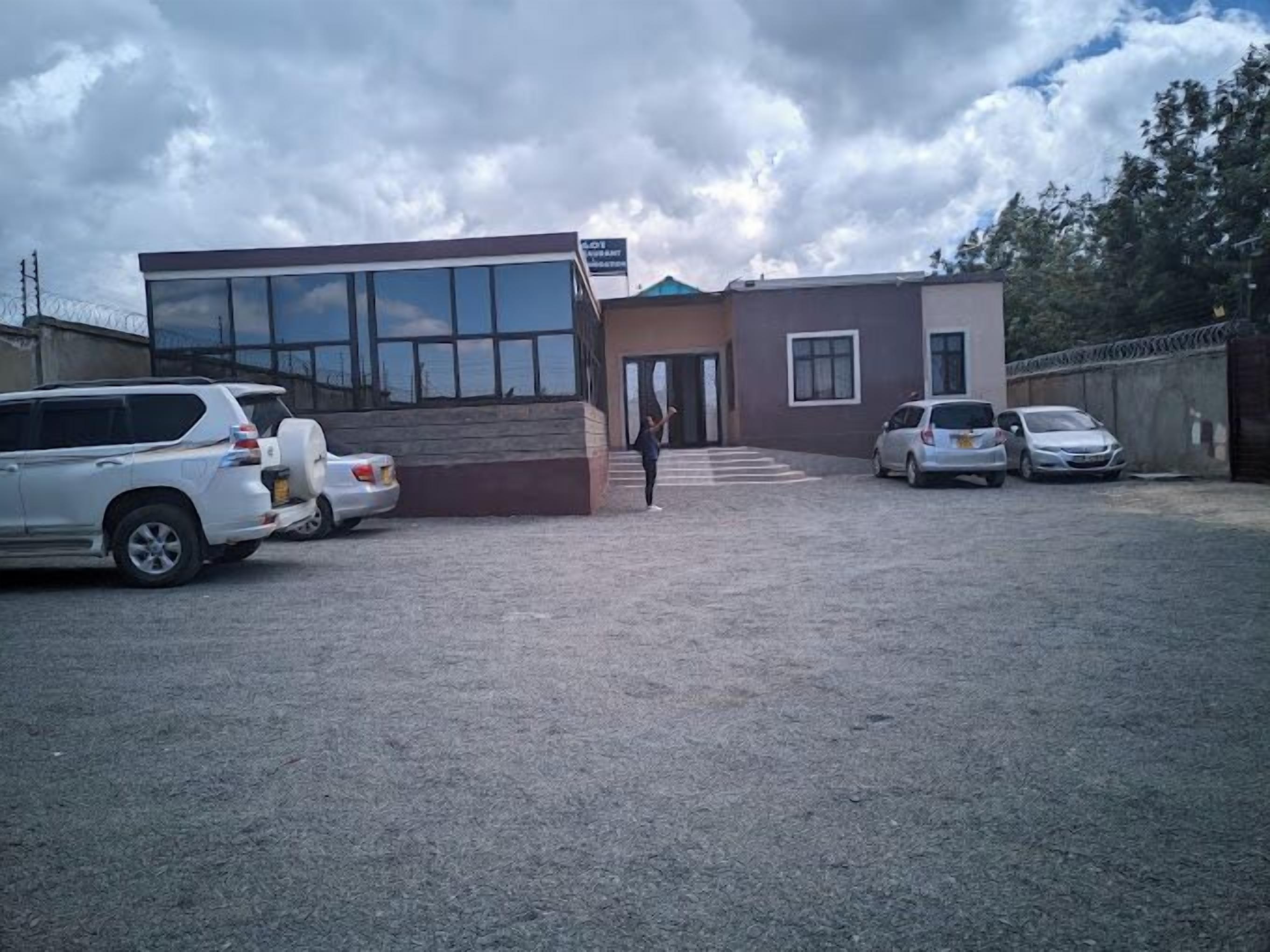 A building with a sign that reads "LOFT AURITE." There are several cars parked in front, and a person is walking towards the entrance.
