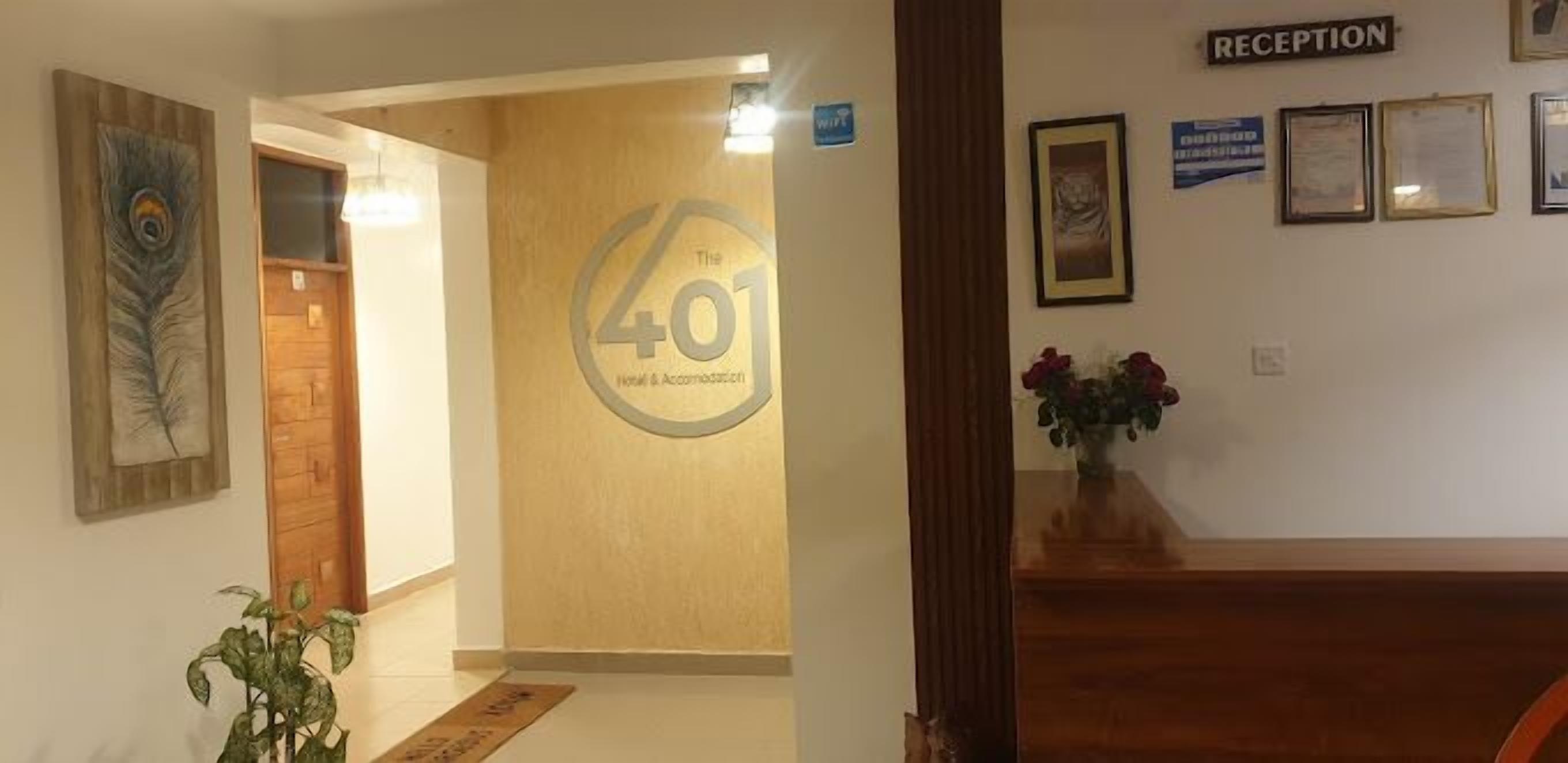Un área de recepción con un mostrador de madera, un letrero en la pared que indica 'Reception' y un gran letrero con el texto 'Hotel & Accommodation'.