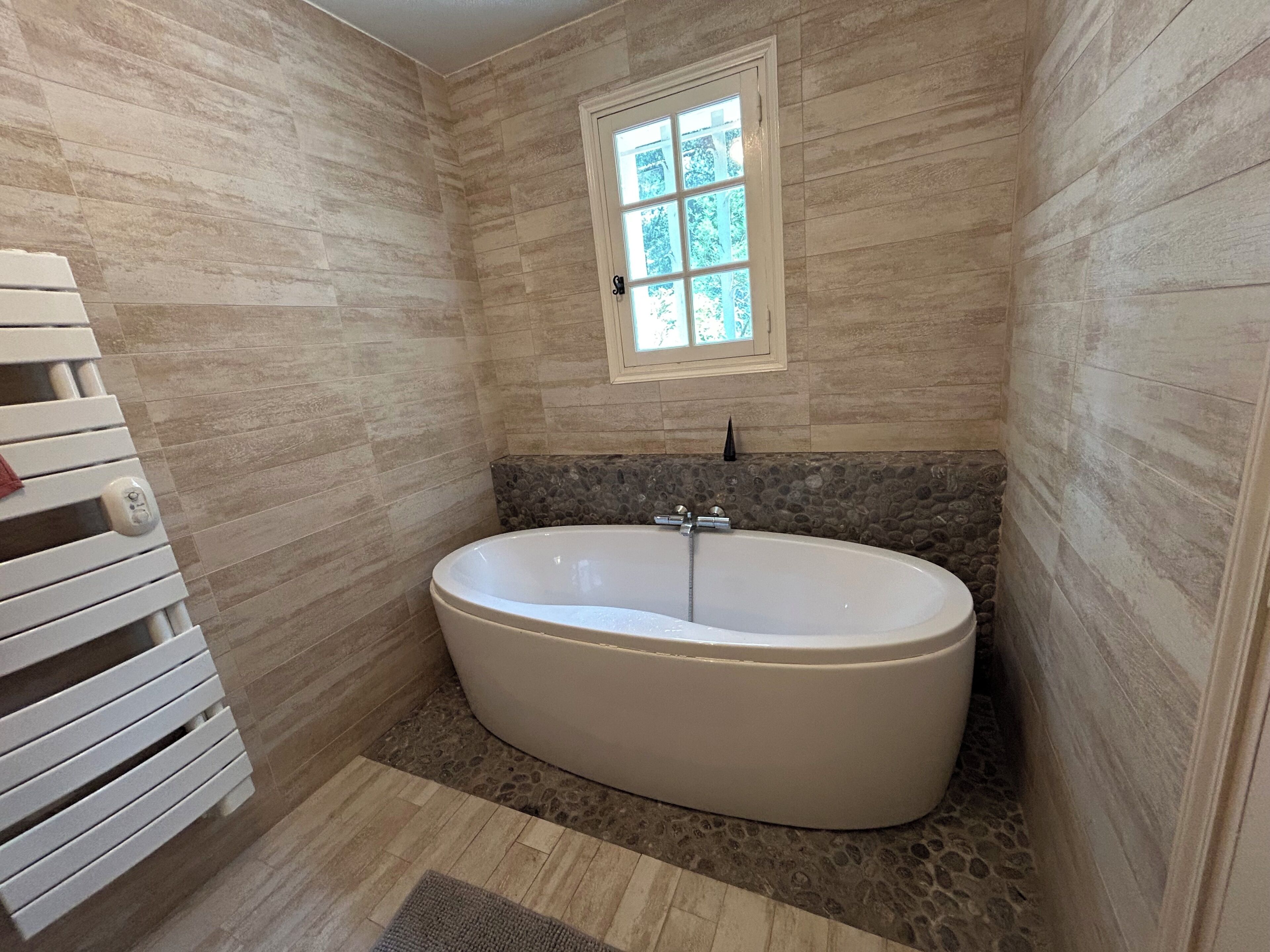 A bathroom with a freestanding bathtub, a window, and a towel rack.