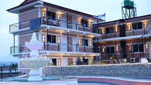 A multi-story hotel with a fountain, outdoor seating, and a water tower. - Shikali Resort (Khokana)