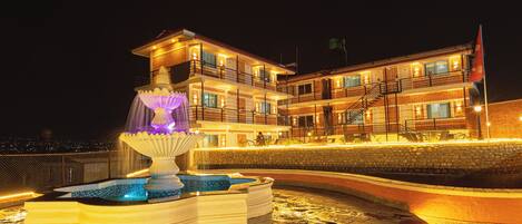 A multi-story hotel with a fountain and pool area.