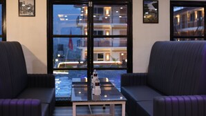 A modern hotel lobby with a glass table, two sofas, and large windows offering a view of the cityscape. - Shikali Resort (Khokana)