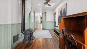 A hallway with a vintage stove, wooden flooring, a ceiling fan, and a wooden cabinet. - Walk to Shopping | 15 Mins to the Resort (Whitefish)
