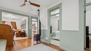 A spacious room with wooden flooring, a ceiling fan, and a large window. - Walk to Shopping | 15 Mins to the Resort (Whitefish)