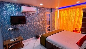 A modern bedroom with a bed, a TV, an air conditioner, and a window with curtains. - Hotel Palace- Near Ruby Hospital (Kolkata)